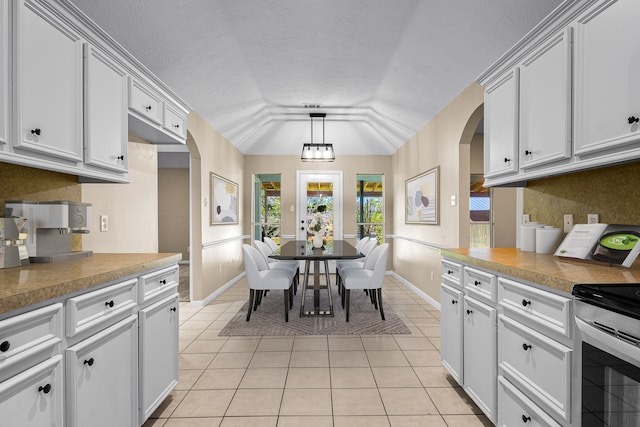 kitchen with electric range, white cabinetry, lofted ceiling, and light tile patterned floors