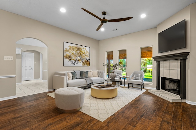 living room featuring ceiling fan, a fireplace, and light wood-type flooring