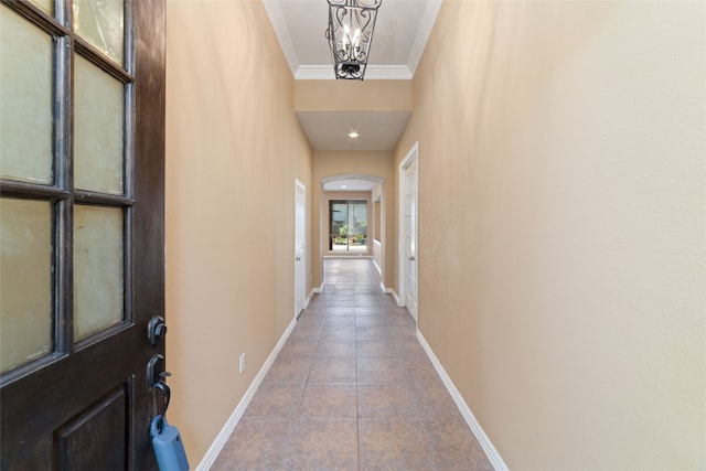 hallway featuring light tile patterned floors, ornamental molding, and an inviting chandelier