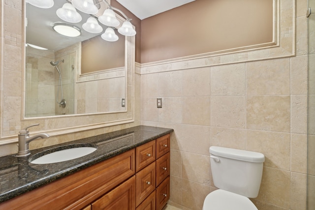 bathroom featuring vanity, toilet, a tile shower, and tile walls