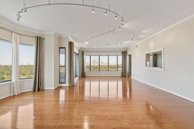 unfurnished room with track lighting, light wood-type flooring, a textured ceiling, and ornamental molding