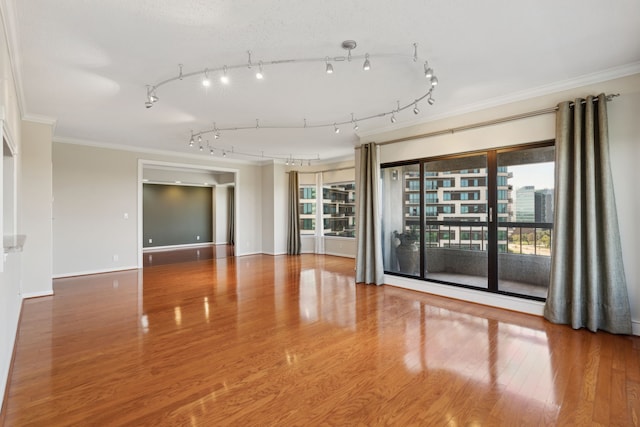 spare room with wood-type flooring, crown molding, and track lighting