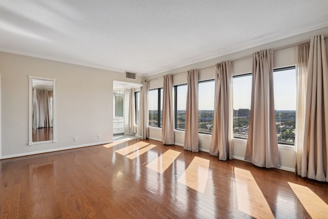 empty room with a textured ceiling, crown molding, and light hardwood / wood-style flooring