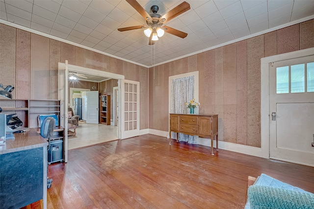 interior space featuring ceiling fan, wood-type flooring, wooden walls, and french doors