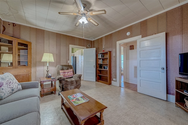 living room with ceiling fan and wood walls