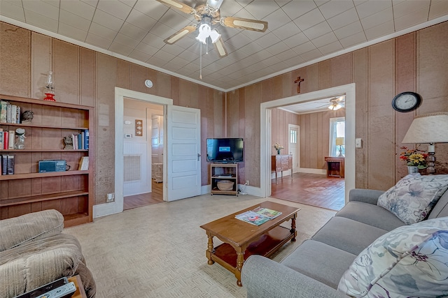 living room with wood walls, light hardwood / wood-style flooring, and ceiling fan