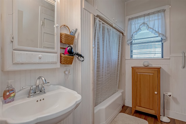 bathroom with hardwood / wood-style floors, shower / bathtub combination with curtain, and sink