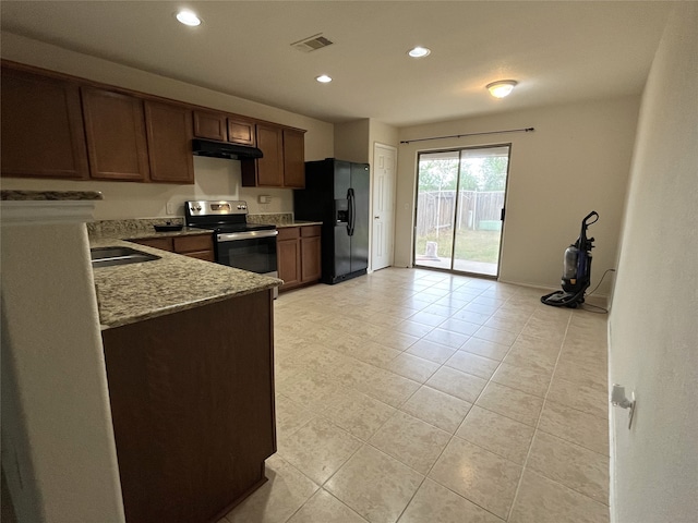 kitchen with light stone countertops, black refrigerator with ice dispenser, stainless steel range with electric stovetop, sink, and light tile patterned flooring