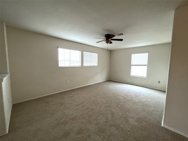 carpeted empty room with ceiling fan and plenty of natural light