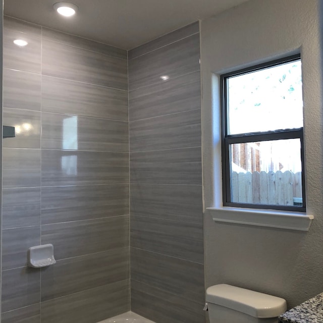 bathroom featuring a tile shower and toilet