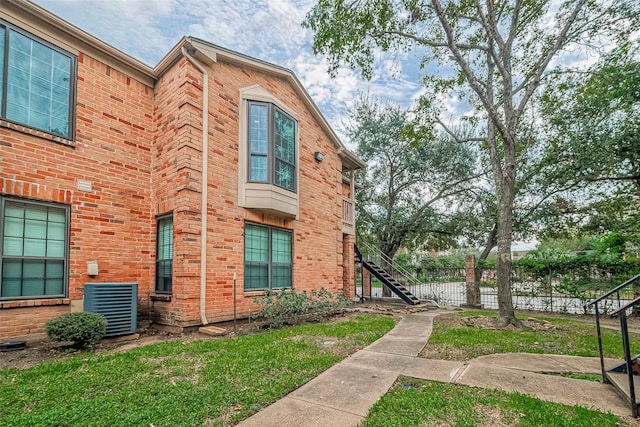 view of side of home with a lawn and central AC unit