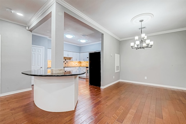 kitchen featuring black refrigerator, white cabinetry, hardwood / wood-style floors, and pendant lighting