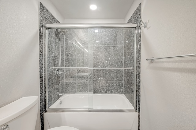 bathroom with bath / shower combo with glass door and toilet