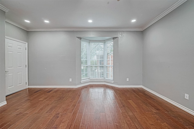 empty room featuring wood-type flooring and ornamental molding