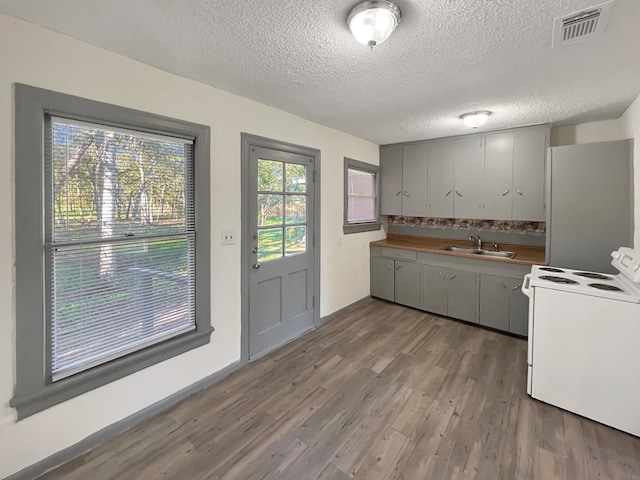 kitchen featuring a textured ceiling, sink, white appliances, and hardwood / wood-style flooring