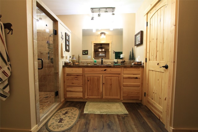 bathroom with hardwood / wood-style flooring, vanity, and a shower with shower door