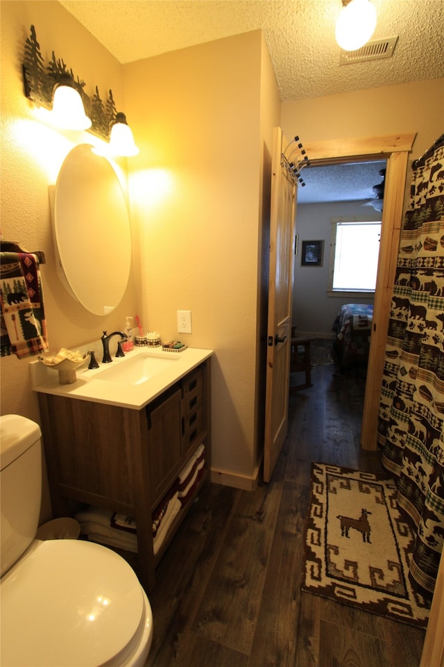 bathroom featuring vanity, wood-type flooring, a textured ceiling, and toilet