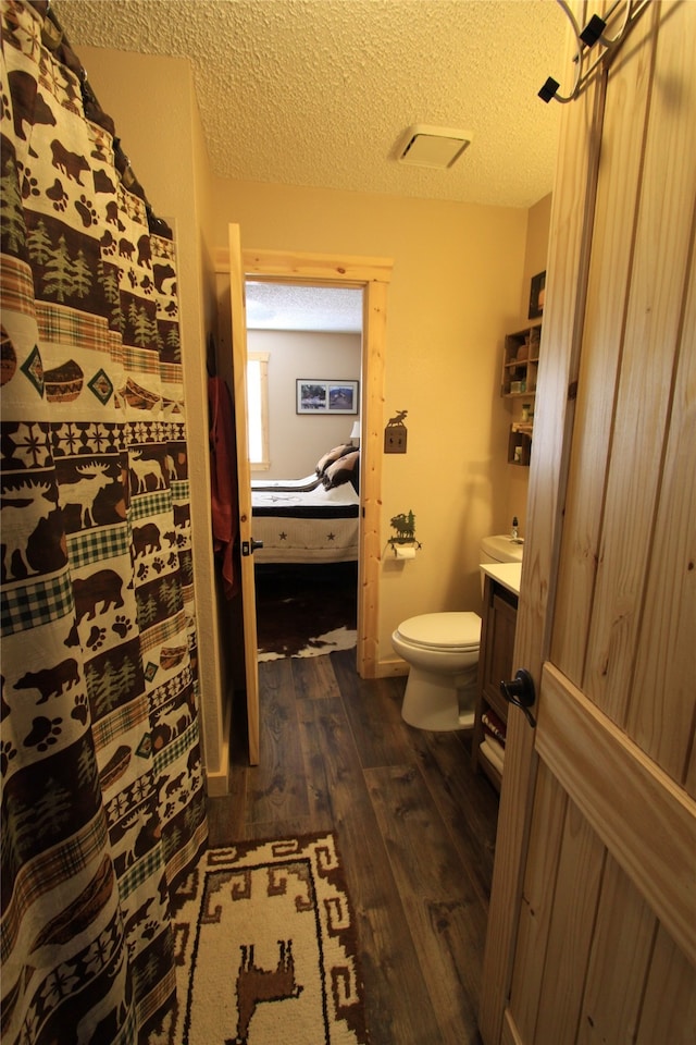 bathroom featuring toilet, vanity, a textured ceiling, and hardwood / wood-style flooring