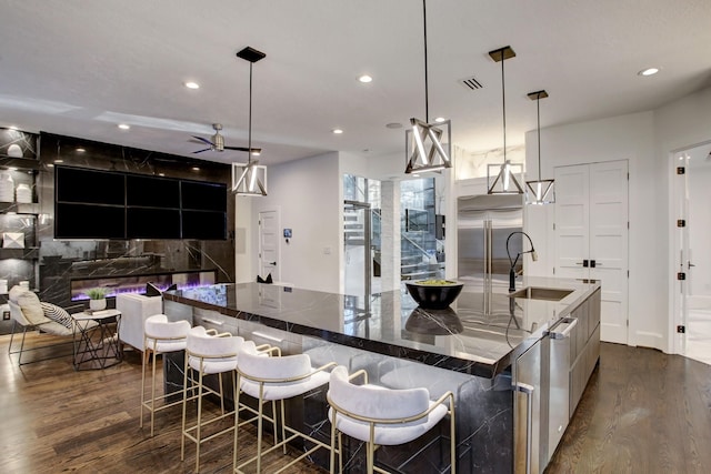 kitchen with pendant lighting, stainless steel built in fridge, a spacious island, and sink