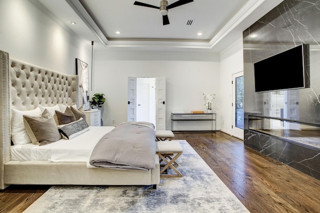 bedroom featuring ceiling fan, dark hardwood / wood-style flooring, ornamental molding, and a tray ceiling