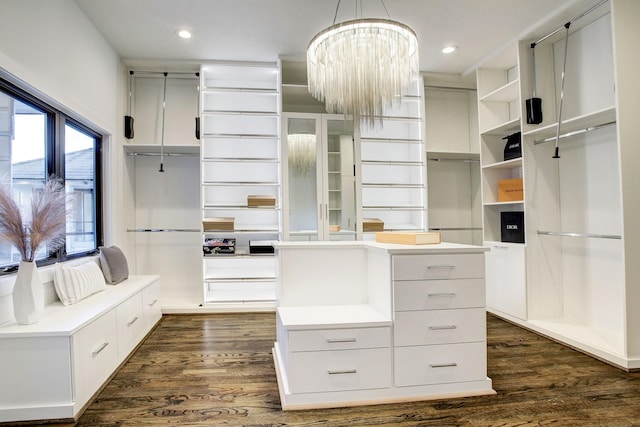 spacious closet with dark hardwood / wood-style floors and a notable chandelier