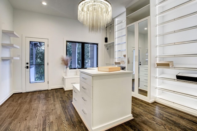 spacious closet featuring dark hardwood / wood-style flooring and a chandelier