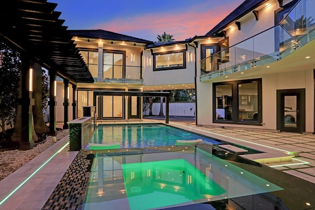 pool at dusk with an in ground hot tub and a patio area