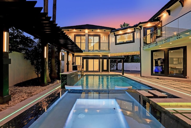 pool at dusk featuring an in ground hot tub