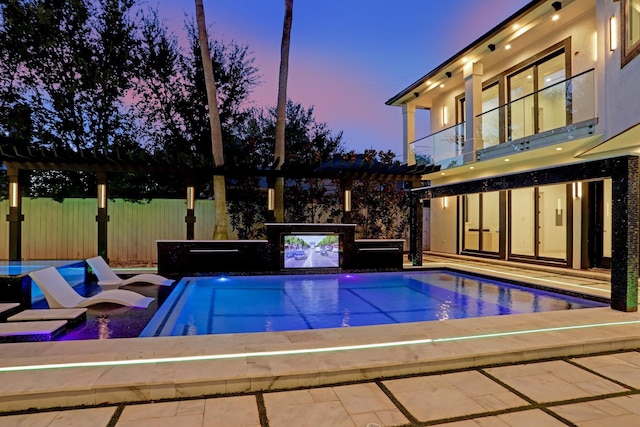 pool at dusk with a pergola and a hot tub