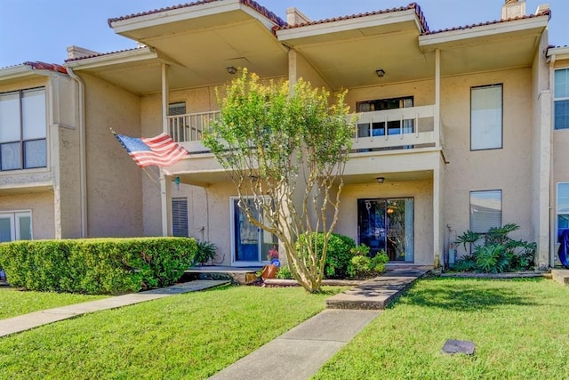 view of front of home featuring a balcony and a front yard