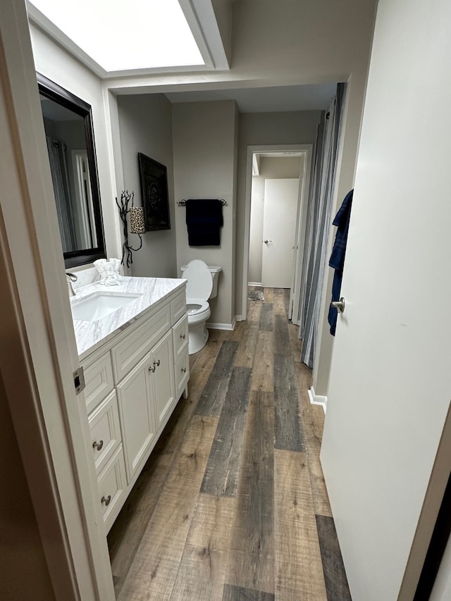 bathroom with toilet, vanity, and hardwood / wood-style flooring