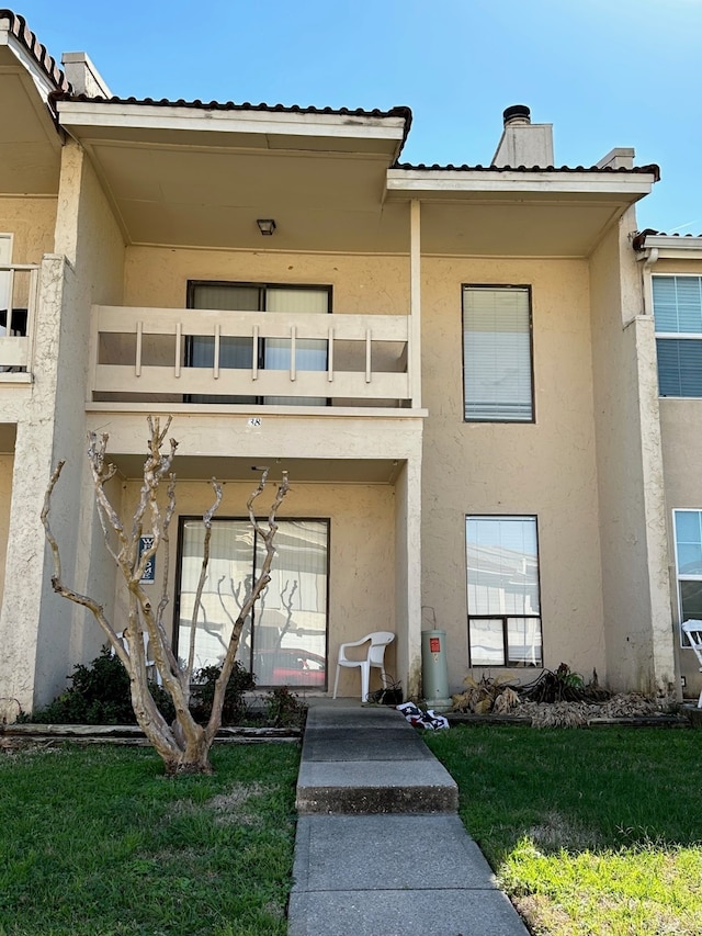 entrance to property with a lawn and a balcony