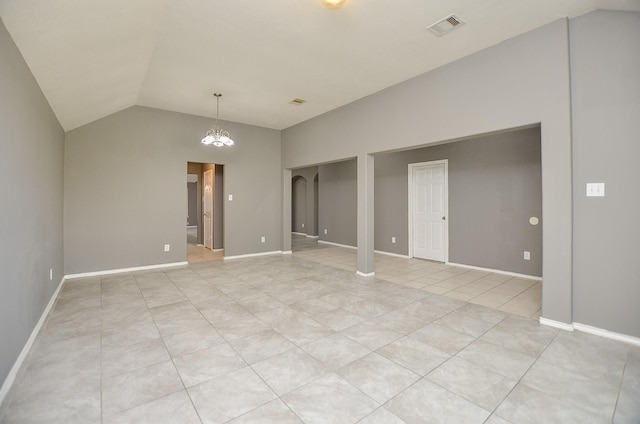 tiled empty room with an inviting chandelier and vaulted ceiling