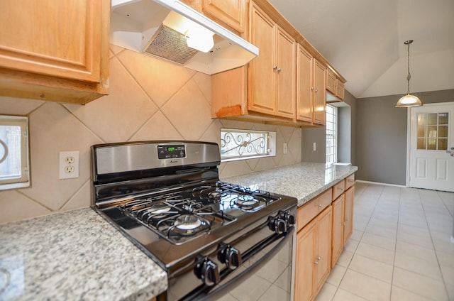 kitchen featuring stainless steel gas stove, light stone counters, backsplash, vaulted ceiling, and light tile patterned floors