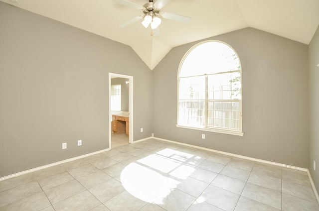 tiled empty room with ceiling fan, a healthy amount of sunlight, and vaulted ceiling