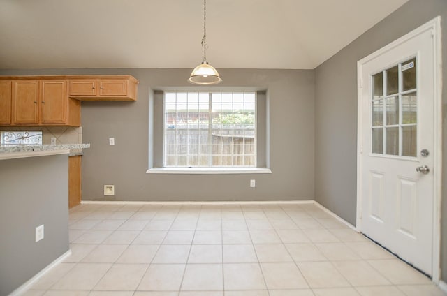 unfurnished dining area with lofted ceiling and light tile patterned floors