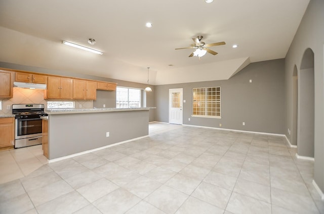 kitchen featuring pendant lighting, stainless steel stove, decorative backsplash, ceiling fan, and light stone counters