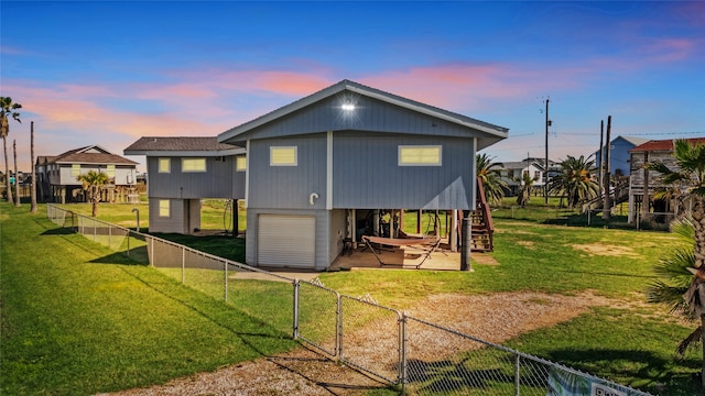 back house at dusk featuring a patio area and a lawn