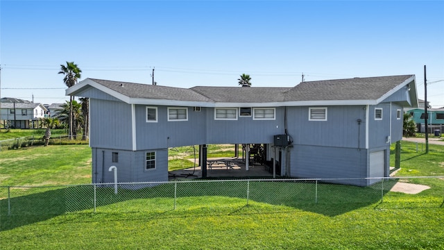 rear view of property featuring a garage and a lawn