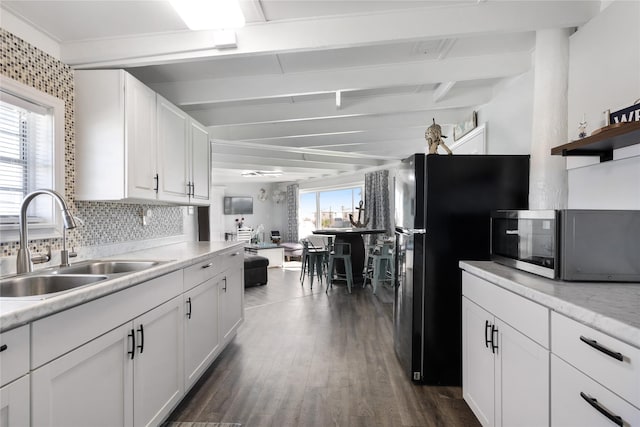 219 Fort Velasco Dr, Surfside Beach, TX 77541 - kitchen with stainless steel microwave, a sink, beamed ceiling, white cabinetry, and dark wood-style floors