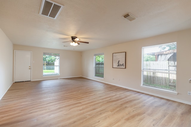 spare room featuring a textured ceiling, light hardwood / wood-style flooring, ceiling fan, and a healthy amount of sunlight