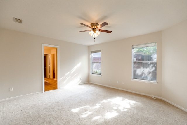 empty room with ceiling fan and light carpet