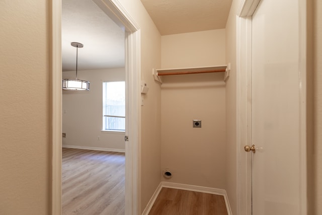 laundry area featuring a textured ceiling, light hardwood / wood-style flooring, and electric dryer hookup