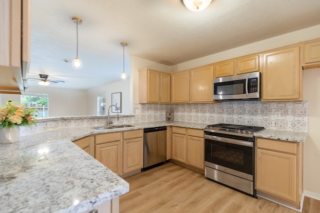 kitchen featuring sink, backsplash, decorative light fixtures, appliances with stainless steel finishes, and light wood-type flooring