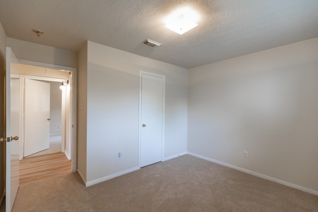 unfurnished bedroom featuring a closet, light colored carpet, and a textured ceiling