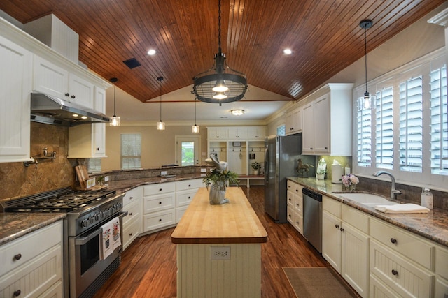 kitchen with a center island, wooden counters, decorative light fixtures, vaulted ceiling, and appliances with stainless steel finishes