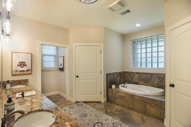 bathroom featuring tile patterned flooring, vanity, a healthy amount of sunlight, and tiled bath