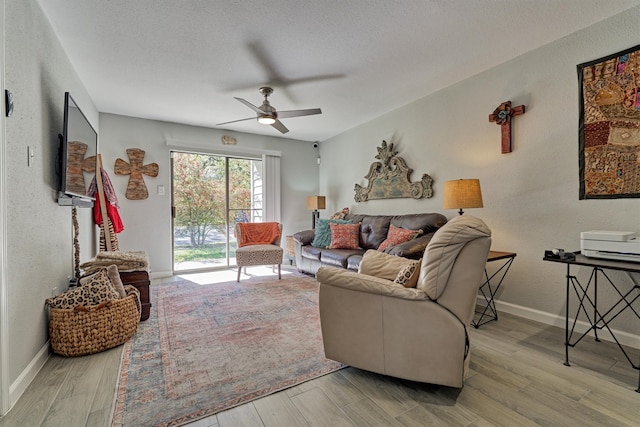 living room with a textured ceiling, light wood-type flooring, and ceiling fan