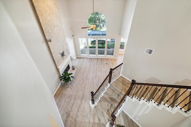 stairway with a high ceiling, hardwood / wood-style floors, and ceiling fan