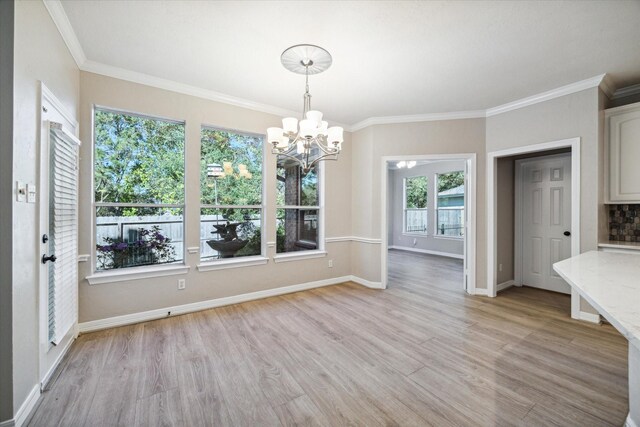 unfurnished dining area with crown molding, a chandelier, and light hardwood / wood-style floors